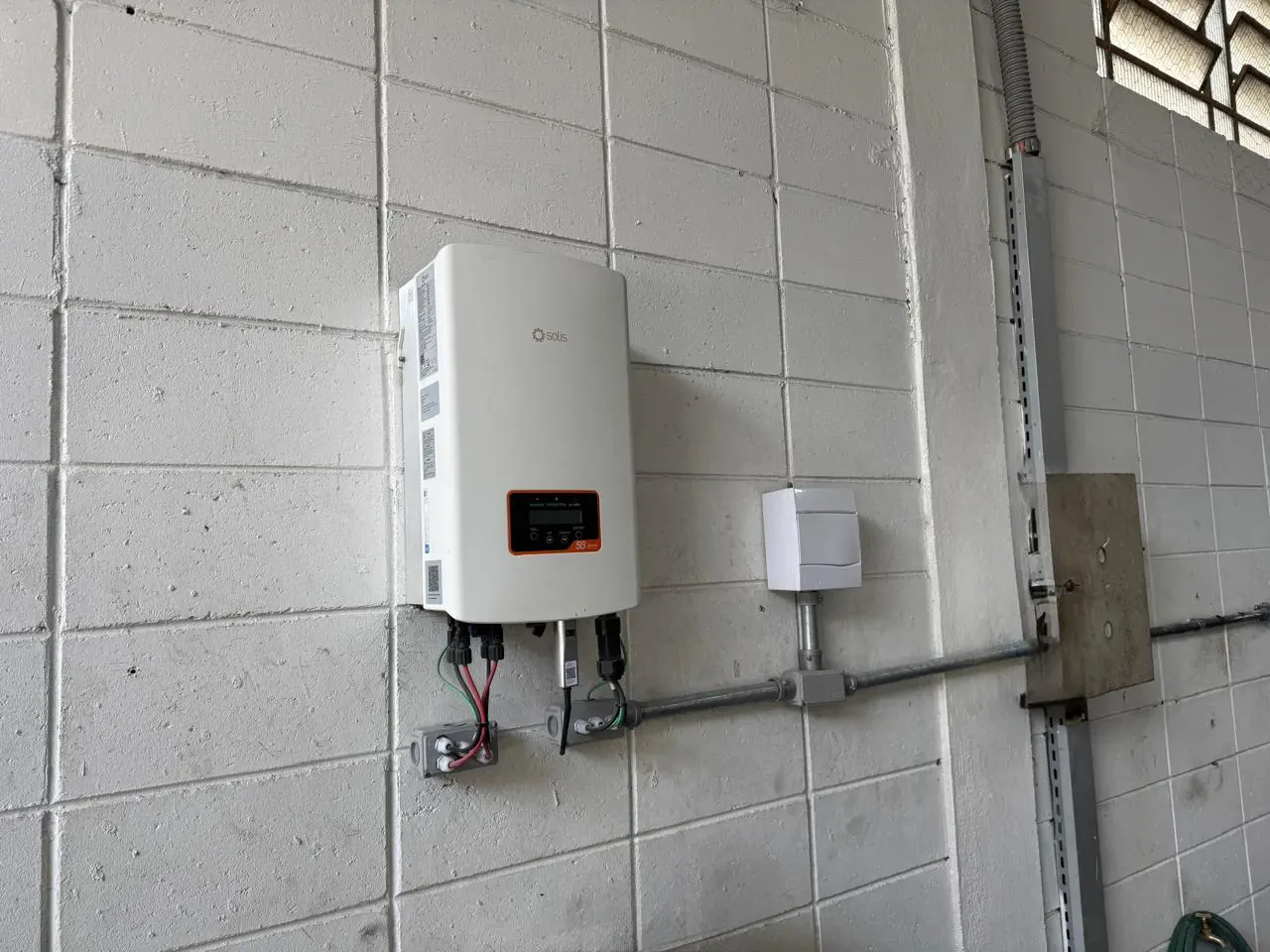 Inversor do sistema de energia solar instalado na parede da oficina, com a fiação em eletroduto