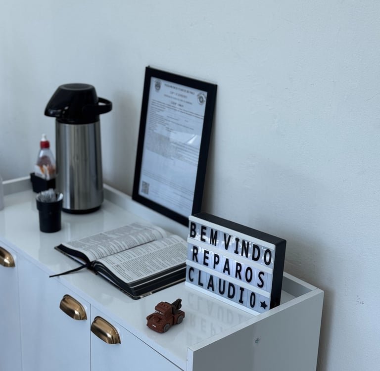 Recepção da oficina com café, Bíblia aberta e o letreiro Bem-vindo Reparos Claudio